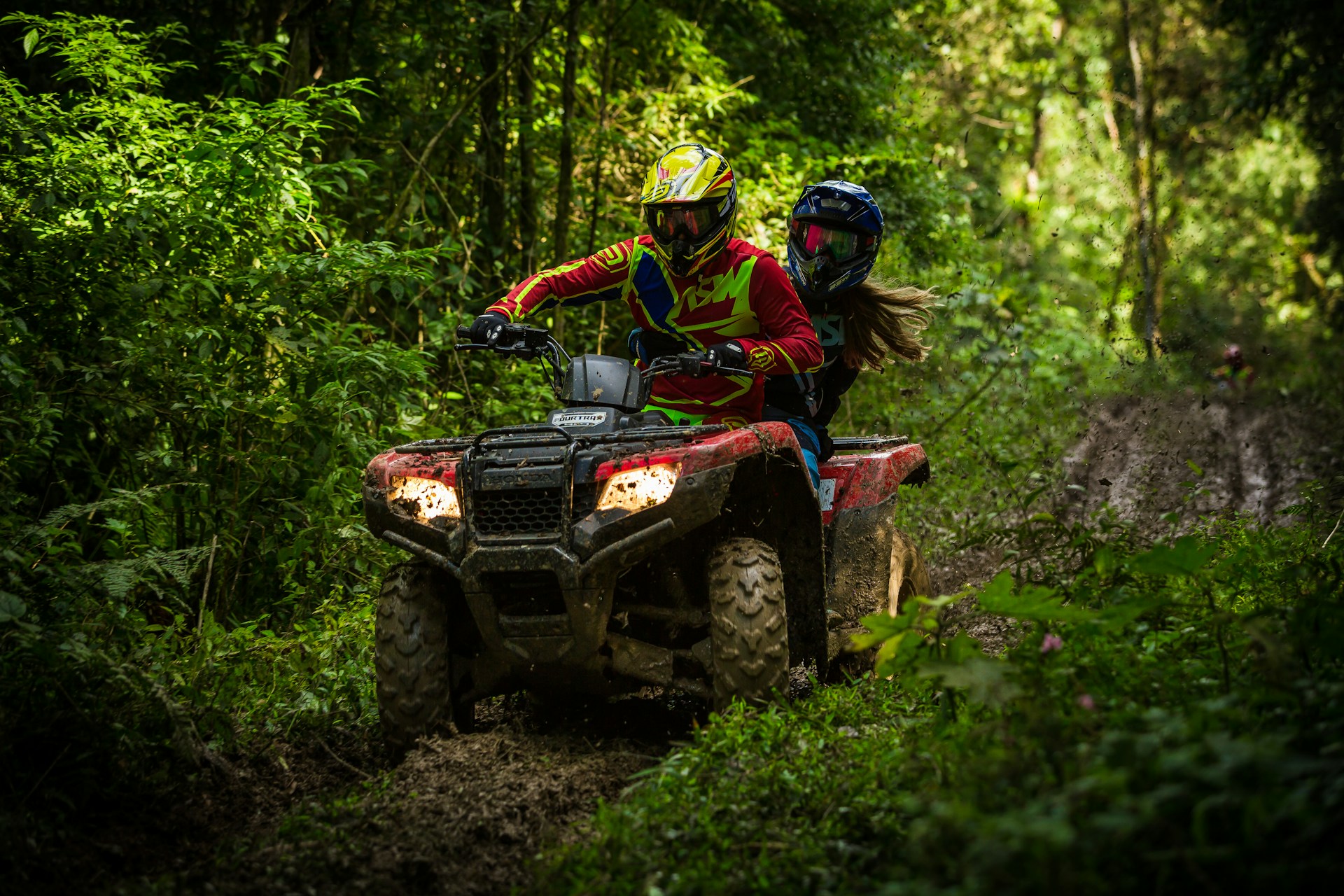 Riders on an ATV through a jungle trail