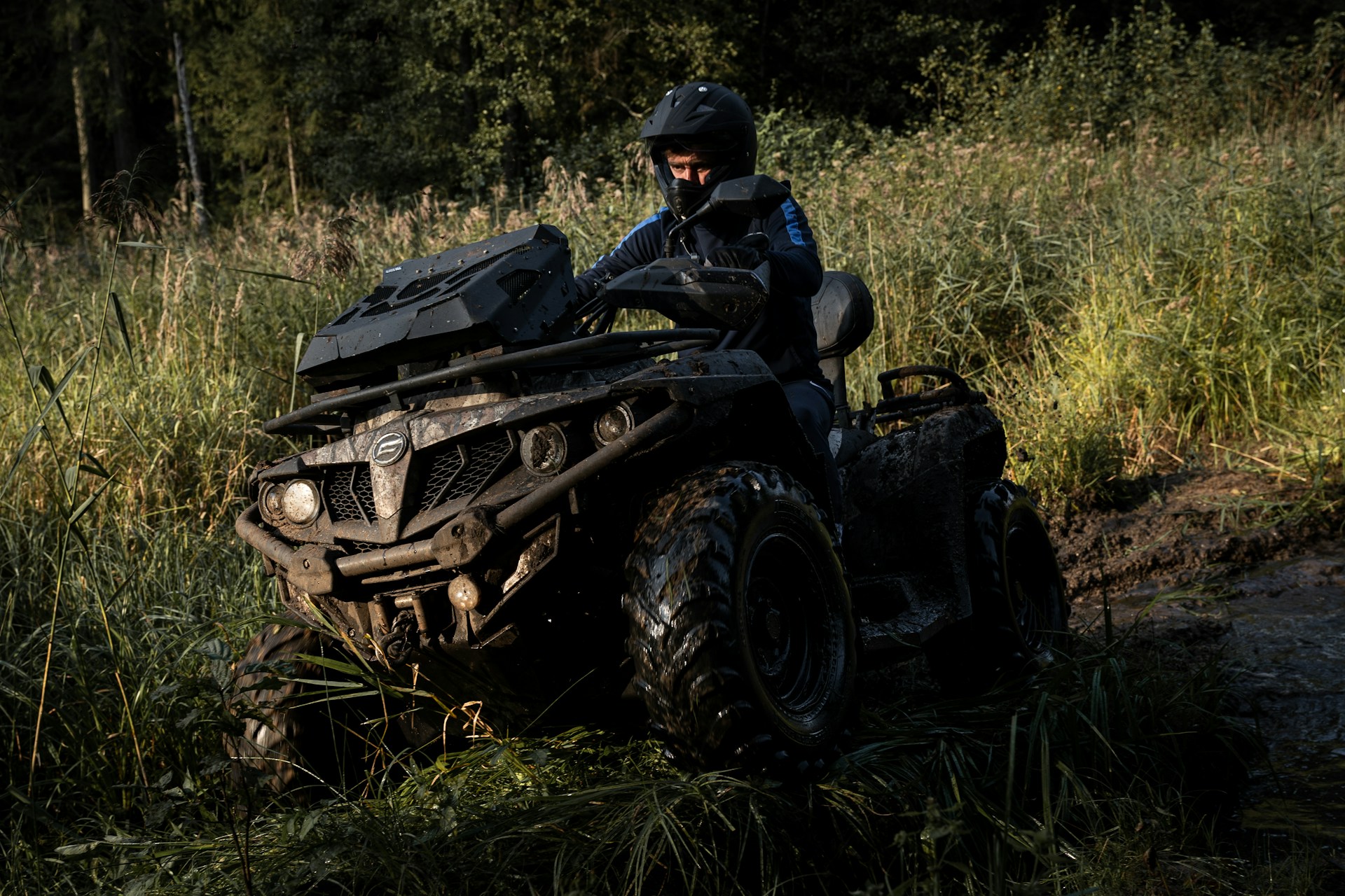 ATV riding through mud and tall grass